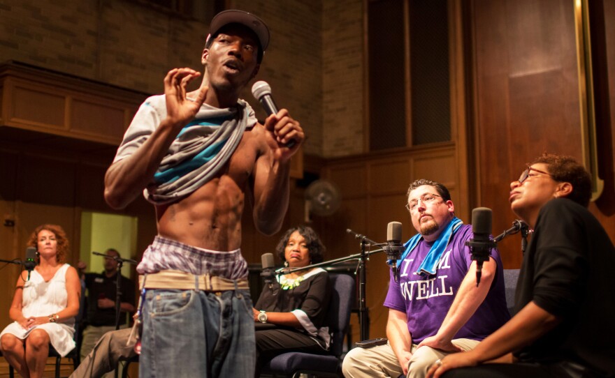 Ferguson resident Frankie Edwards shows a rubber bullet wound he suffered during one of the nights of protests to NPR's Michel Martin (right) and Ferguson Mayor James Knowles (second from right) during the community conversation at Wellspring Church.