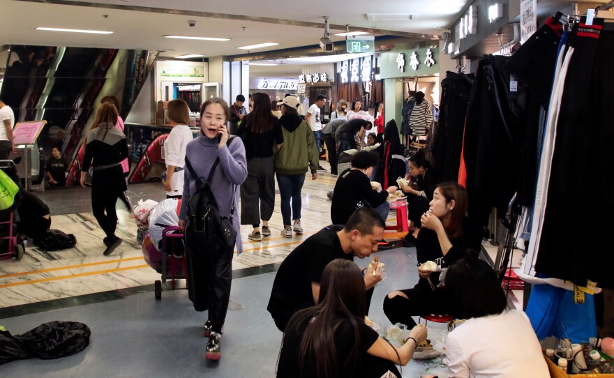 Merchants eat lunch in their stalls at Beijing's largest wholesale clothing market. Merchants complain that the government wants them to move out of Beijing, but has offered them no compensation