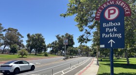 A car drives past a sign directing traffic to Balboa Park's parking lots and free tram service, July 28, 2025.
