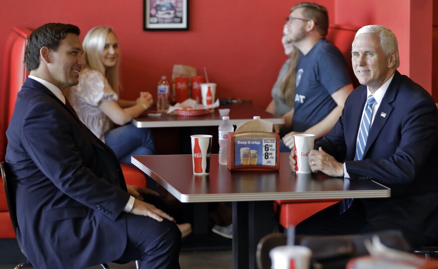 Florida Gov. Ron DeSantis (left) talks to Vice President Pence as they wait for their lunch at Beth's Burger Bar in Orlando, Fla., on May 20.