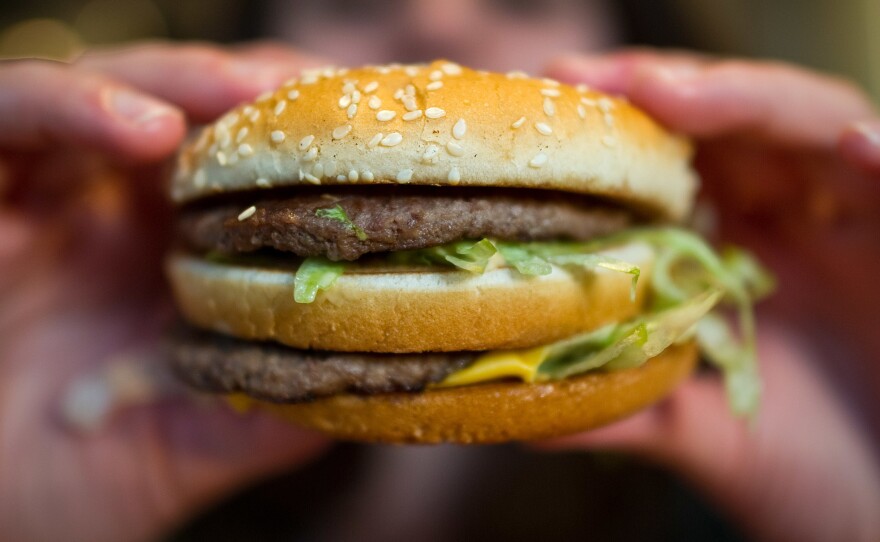 A customer holds a McDonald's Big Mac. The fast-food giant, one of the world's biggest beef buyers, has announced plans to use its might to cut back on antibiotics in its global beef supply. Environmentalists are applauding the commitment.