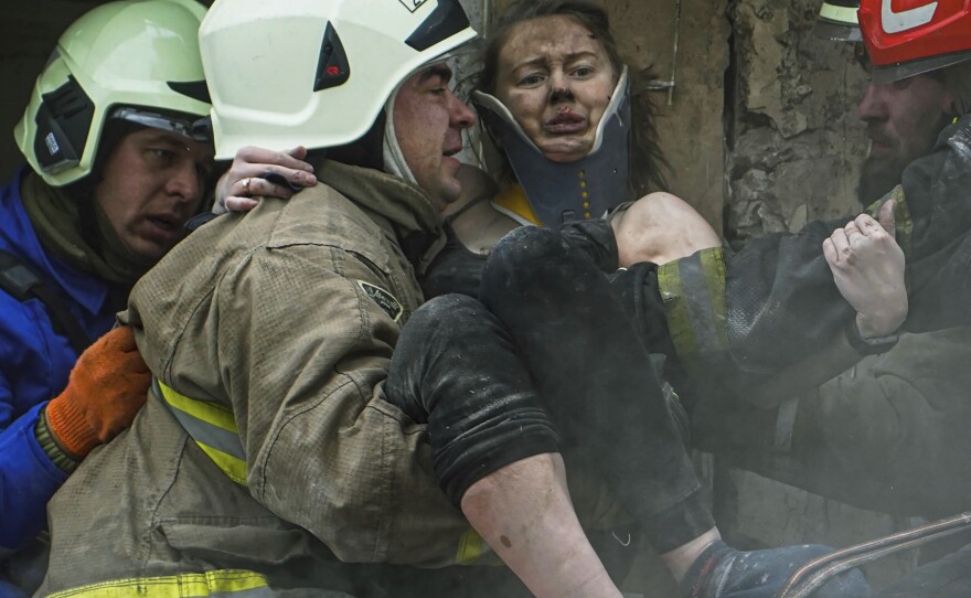 In this photo released by the State Emergency Service of Ukraine, firefighters carry a wounded woman out of the rubble of a building after a Russian rocket attack on Saturday in Dnipro.
