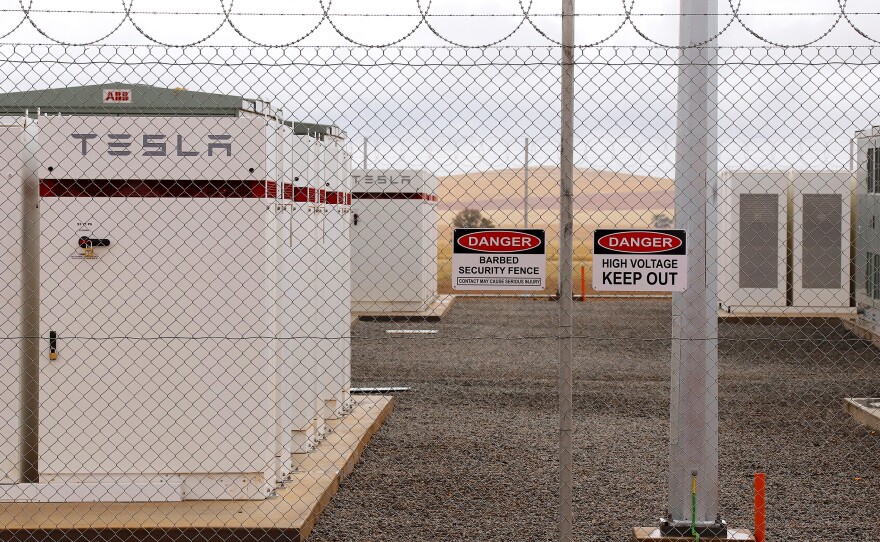 Warning signs adorn the fence surrounding the compound housing the Hornsdale Power Reserve, featuring the world's largest lithium ion battery made by Tesla, during the official launch near Jamestown, Australia, on Friday.