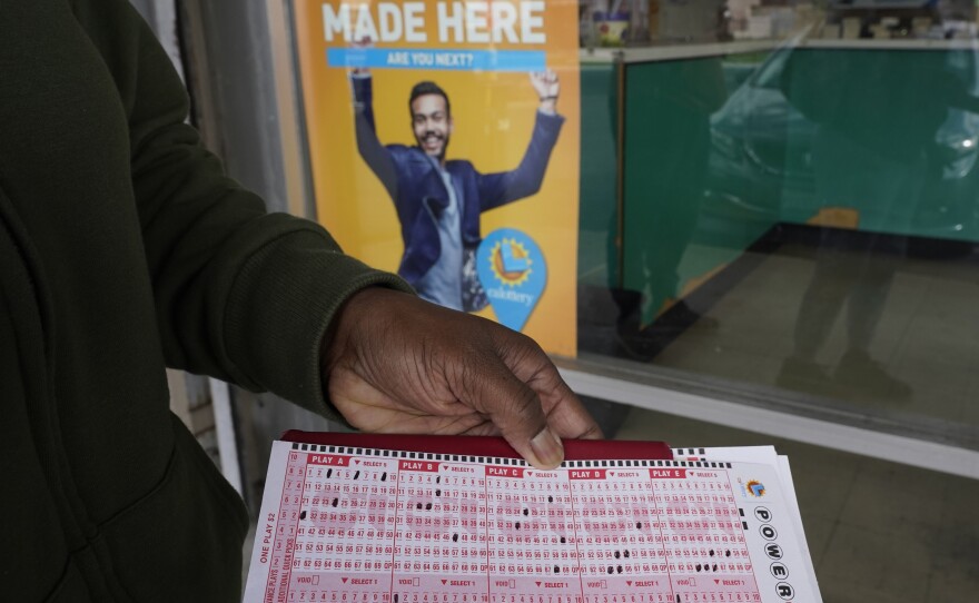 A lottery player displays their Powerball picks as they wait in line to purchase tickets at Lichine's Liquor & Deli in Sacramento, Calif., Monday, Nov. 7, 2022. Monday night's drawing was at an estimated $1.9 billion.