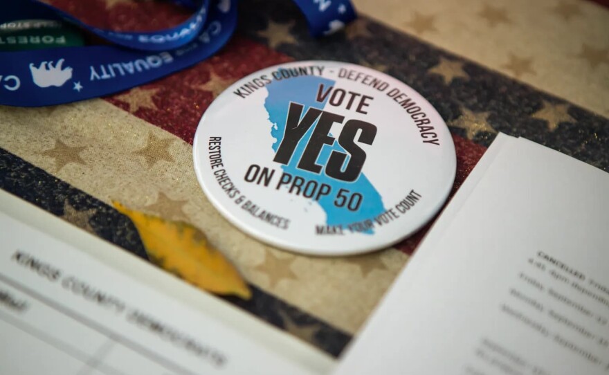 A button reads, “Vote Yes on Prop 50” at the Kings County Democrats booth during the Thursday Night Marketplace in downtown Hanford on Sept. 25, 2025. 