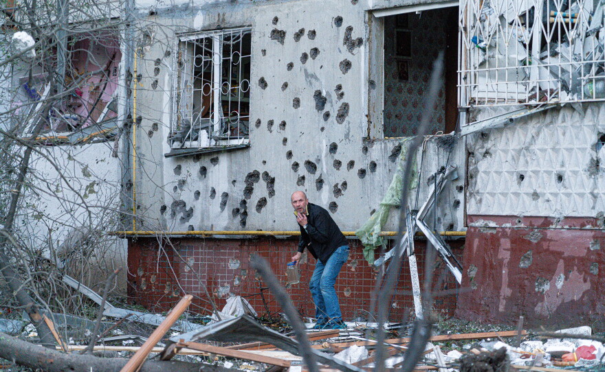 A man cowers outside a damaged building in Kyiv after Russia's latest attack.