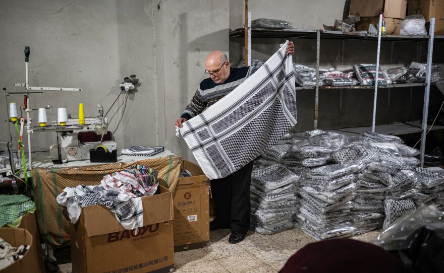 Judeh Hirbawi folds a keffiyeh at the factory, on Feb. 11, 2024.