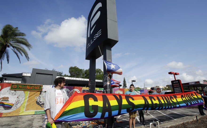 Activists hold a banner in front of the Pulse nightclub site on Thursday in Orlando, Fla.