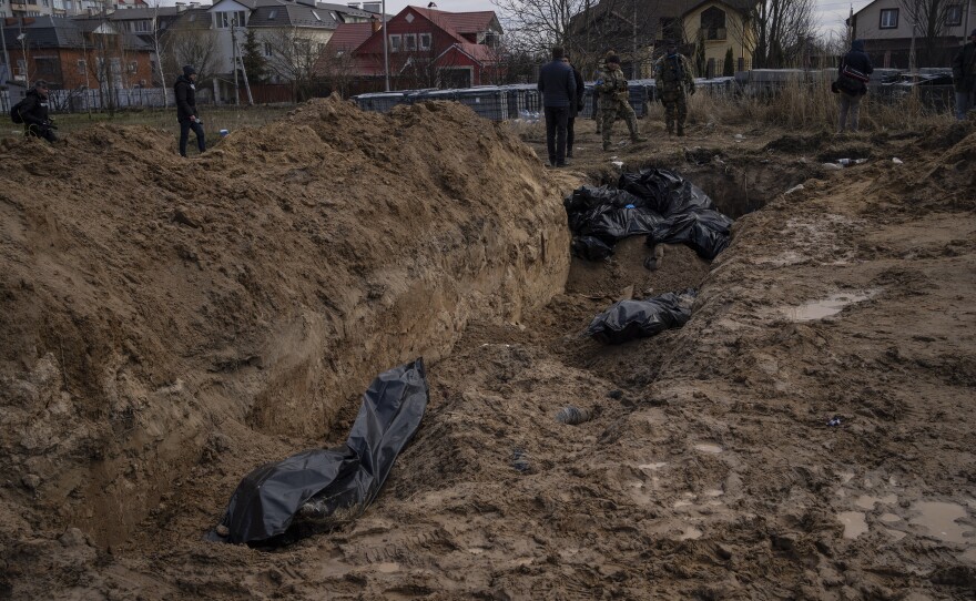 Journalists stand by a mass grave in Bucha on Monday.