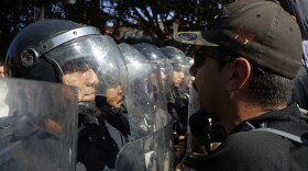 Police stand guard to protect a migrant shelter as demonstrators protest the presence of thousands of Central American migrants in Tijuana, Mexico, Sunday, Nov. 18, 2018.