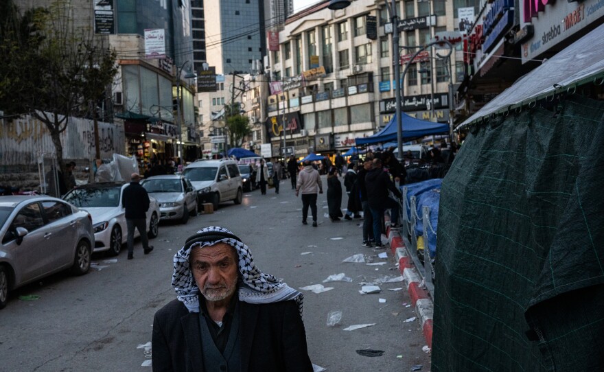 A man wearing a traditional Palestinian keffiyeh walks down a street in Hebron.