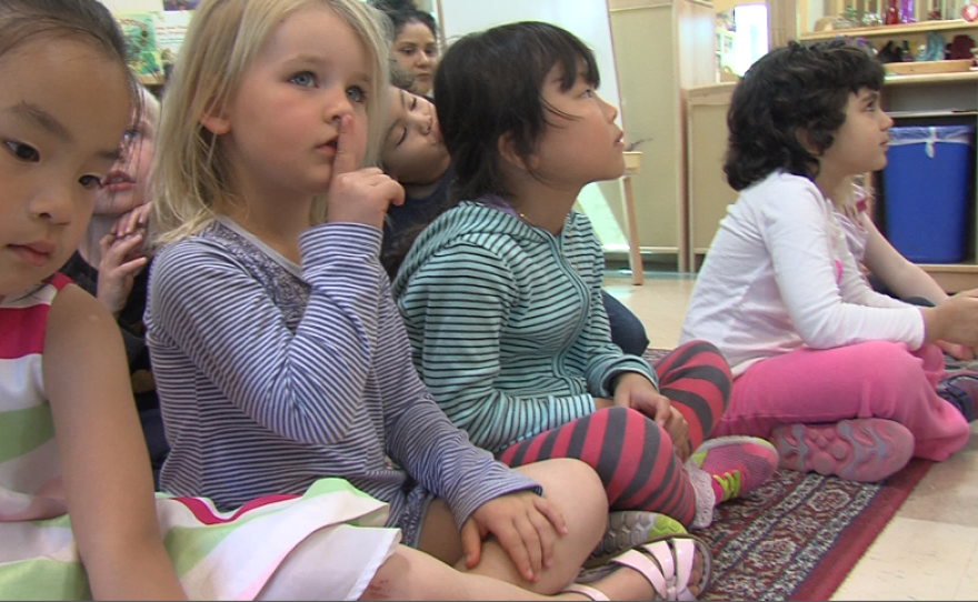 A child at the Mesa Child Development Center puts her finger to her lips as part of a routine to bring students from controlled chaos outside to upright and facing forward inside, April 13, 2017.