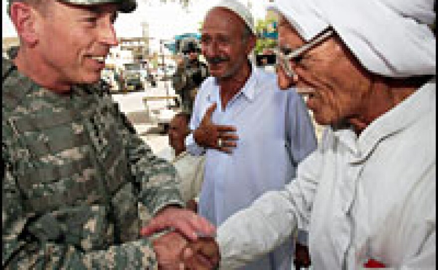 Petraeus (left) greets Iraqi men at a tea shop.