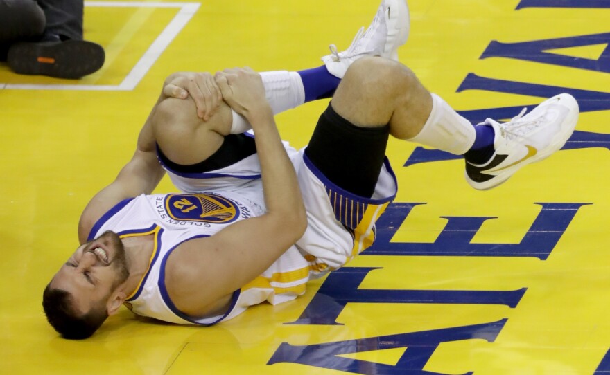 Andrew Bogut of the Golden State Warriors holds his knee in pain after sustaining an injury in the third quarter Monday night in Oakland.