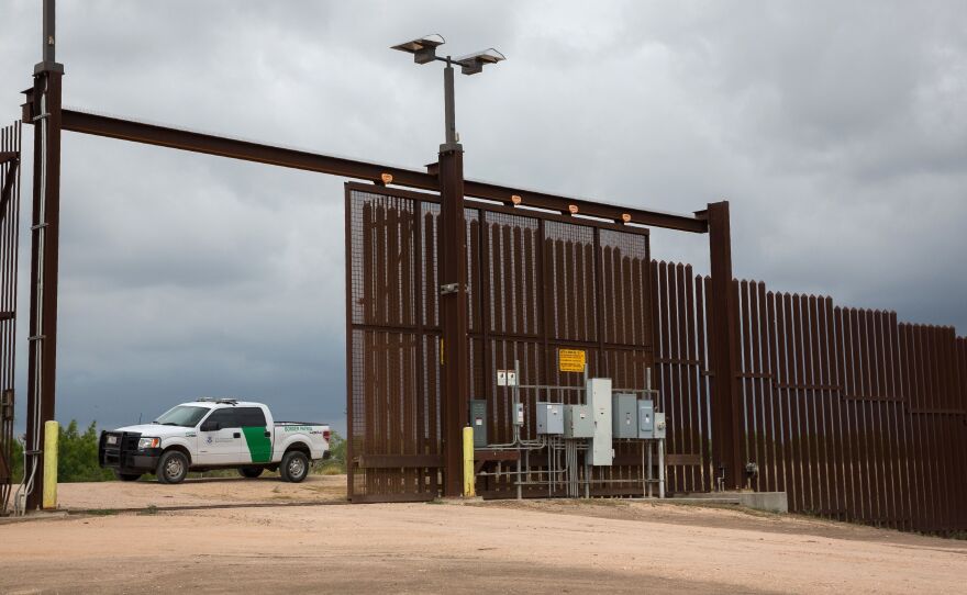 A U.S. Border Patrol agent keeps watch at a gate on the U.S.-Mexico border fence near San Benito, Texas.