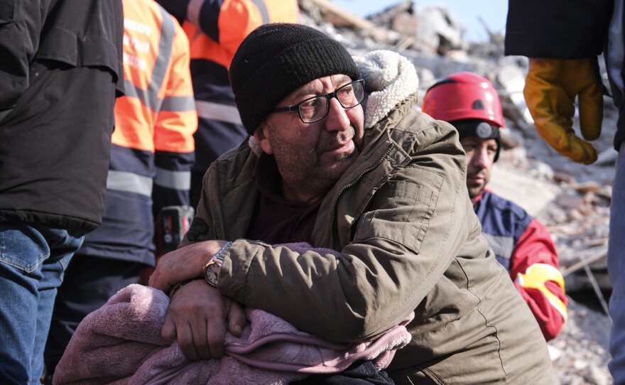 A man watches rescue teams work on a collapsed building to evacuate a victim in Elbistan, Turkey.