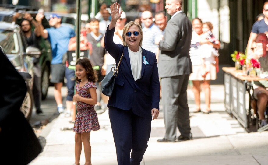 Hillary Clinton waves as she leaves an apartment building Sunday. Earlier in the day, she fell ill at a Sept. 11 commemoration event.