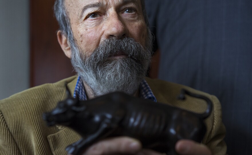 Arturo Di Modica holds a model of his <em>Charging Bull</em> during a news conference Wednesday.