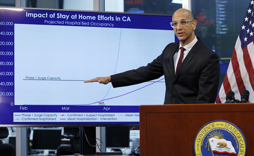 In this April 1, 2020, file photo Dr. Mark Ghaly, secretary of the California Health and Human Services, gestures to a chart showing the impact of the mandatory stay-at-home orders, during a news conference in Rancho Cordova, Calif.