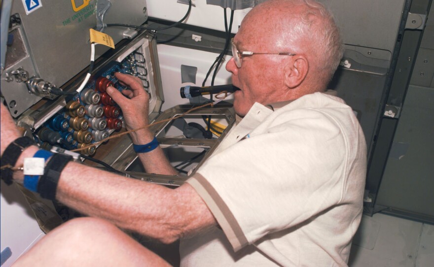 Glenn checks out support equipment for an experiment during the shuttle's orbit above Earth on Nov. 4, 1998.