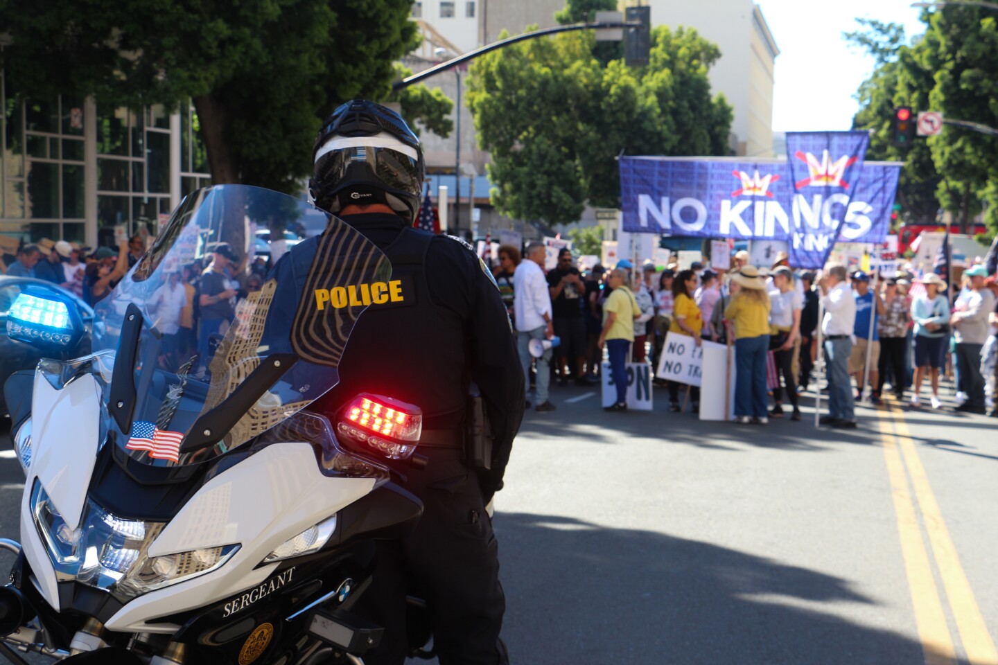 A San Diego police officer watches a crowd of "No Kings" protestors in downtown San Diego on Oct. 18, 2025.