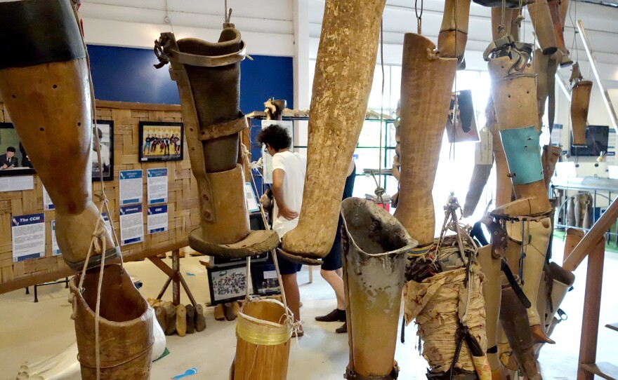 Homemade artificial limbs hang at the COPE Visitor Center. The Cooperative Orthotic and Prosthetic Enterprise is a nonprofit organization in Laos. The makeshift prosthetic legs, some of them clearly just rudimentary pieces of sanded wood, were donated by bombing survivors after use.