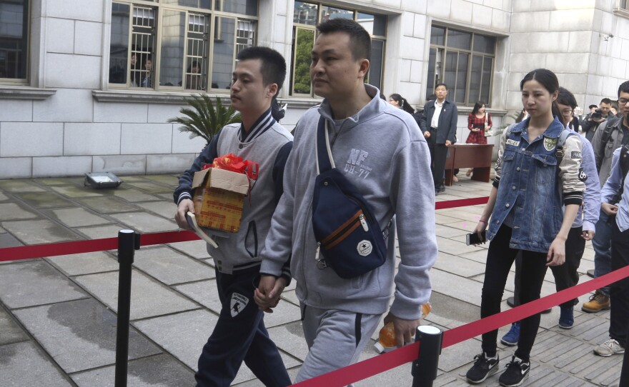Sun Wenlin (left) and his partner, Hu Mingliang, hold hands as they arrive at the Furong District Court in Changsha to argue in China's first same-sex marriage case.