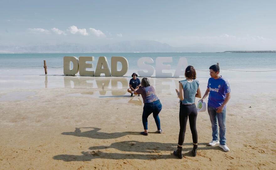 Tourists take pictures near a Dead Sea sign near an Israeli hotel resort.