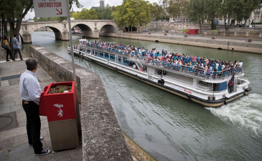 A man stands at a Uritrottoir public urinal on the Île Saint-Louis in Paris.