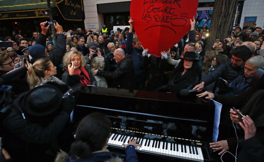 A woman plays piano, next to a red heart reading "Love runs through the streets," in front of the Bataclan concert hall in Paris on Sunday. The city marked the one-year anniversary of the Nov. 13, 2015, attacks that targeted the concert hall and several other sites, killing 130 people.