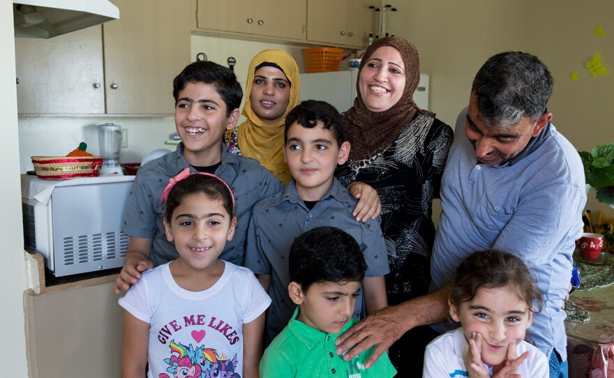 Mohamad Abdullah (far right), touches the shoulder of his son during a family photo in kitchen of the family's two-bedroom El Cajon apartment, July 25, 2017.
