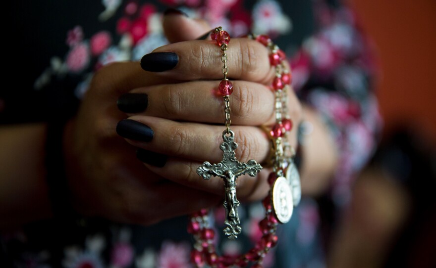 Shawn's wife holds a string of rosary beads that she uses when she prays.