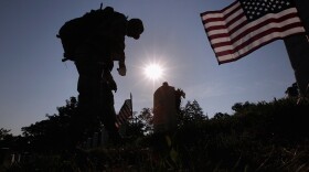 Members of the 3rd U.S. Infantry Regiment place American flags at the graves of U.S. soldiers buried at Arlington National Cemetery in preparation for Memorial Day May 26, 2011 in Arlington, Virginia.