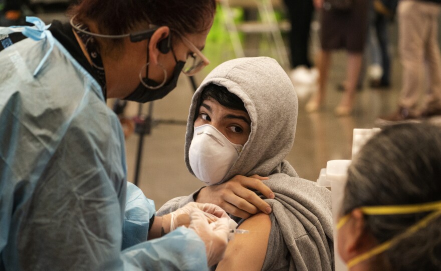 A student looks back at his mother, as he is vaccinated at a school-based COVID-19 vaccination clinic for students 12 and older in San Pedro, Calif., last month.