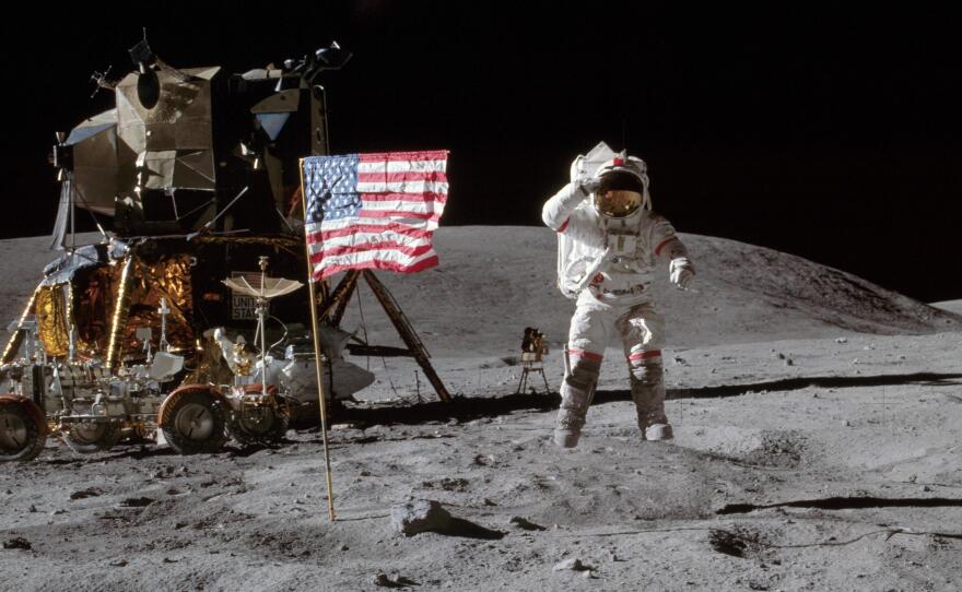 On the moon in 1972, Apollo 16 astronaut John Young jumps off of the lunar surface to salute the U.S. flag.