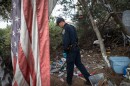 California Highway Patrol Officer Jesse Matias looks through an encampment near a freeway in San Diego, April 28, 2022.