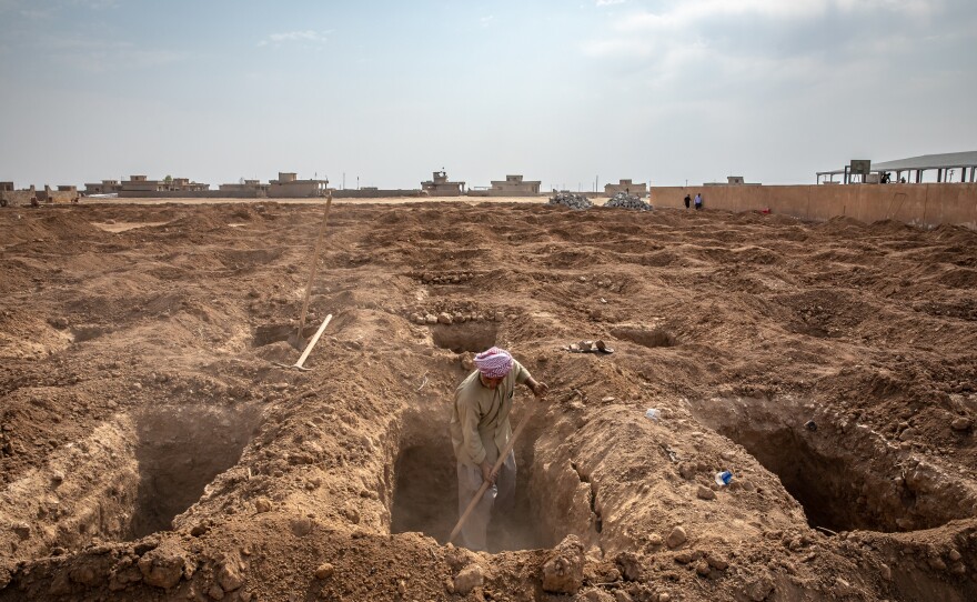 A man from a group of Yazidi survivors and volunteers digs new graves in 2019 to properly bury family members whose remains were discovered in mass graves in the Yazidi village of Kocho, northern Iraq. Now, a year later, many family members are still waiting for the bodies to undergo DNA testing and be returned to them.