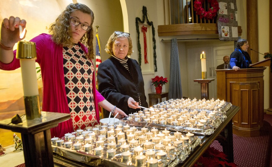 Elizabeth Hadley and Lisa Barbin light candles at the 28th annual Interfaith Homeless Memorial Service to remember homeless people who died in Boston in 2017.