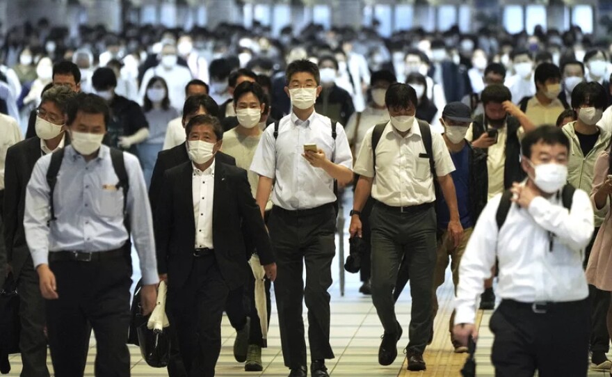 Commuters wearing face masks to help curb the spread of COVID-19 during rush hour at the Shinagawa train station in Tokyo on Oct. 1. Case numbers have dropped significantly in Japan since summer. Researchers are trying to determine why. One theory is that the willingness to wear masks has made a difference; other theories are being investigated.