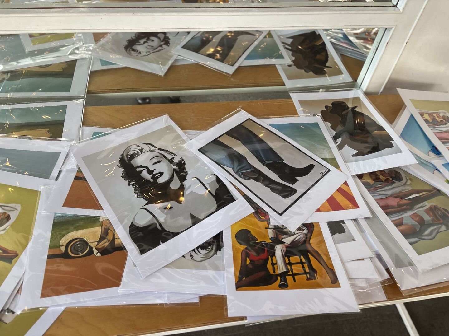 Prints of Fredo Gillis' art scattered across a table for visitors to look through and purchase at his solo art show on Sept. 28, 2025.