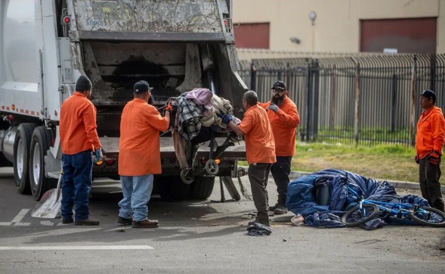 Fresno Police and city workers conduct a homeless encampment sweep under a highway overpass in downtown on Feb. 3, 2025.