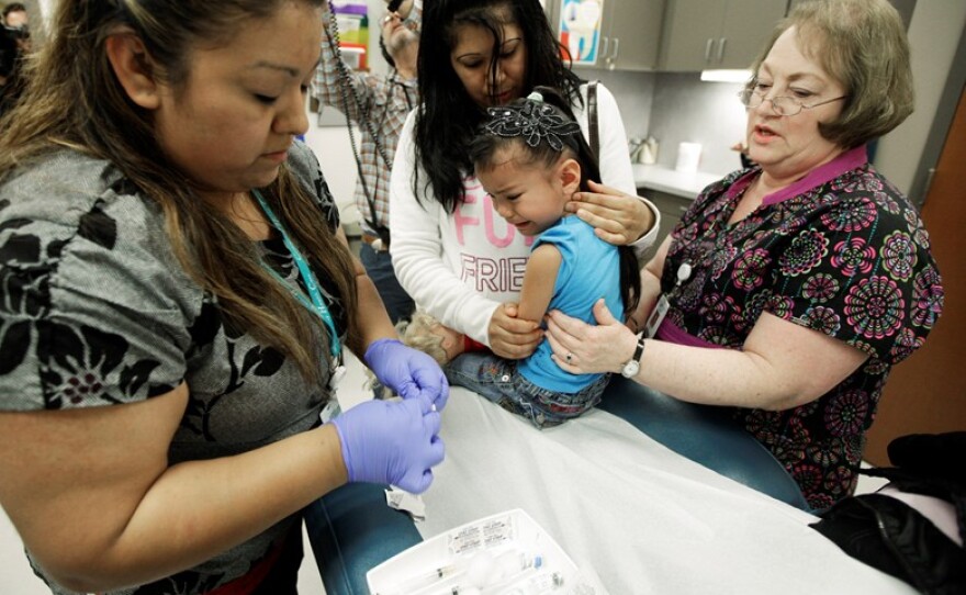 Nurses Fatima Guillen, left, and Fran Wendt, right, give Kimberly Magdeleno, 4, a whooping cough booster shot, as she is held by her mother, Claudia Solorio, at a health clinic in Tacoma, Washington, May 3, 2012.
