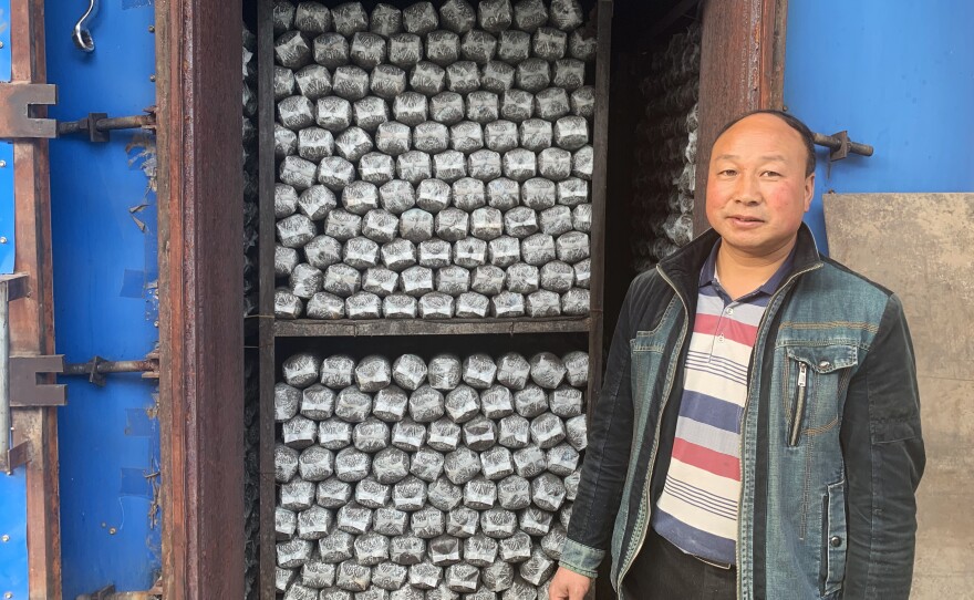 Sun Dahui, a mushroom co-op manager, stands outside a self-made oven, which heats logs of mushroom-growing medium. The cooperative hopes to expand into making mushroom-based sauces soon.