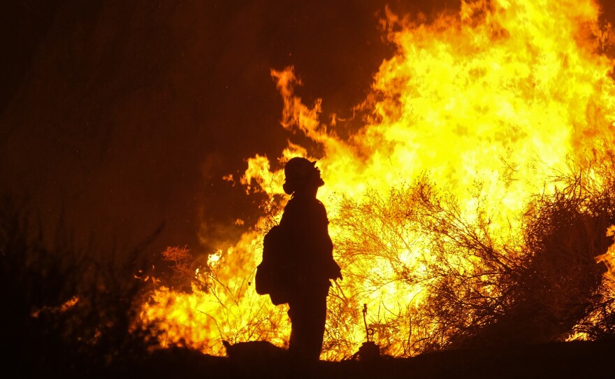 A firefighter looks on as the Holy Fire consumes a hillside Thursday in Temescal Valley in Corona, Calif.
