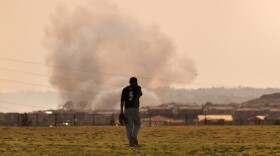 A baseball player walks to the outfield at Del Norte High School as the Bernardo Fire rages in the background. May 13, 2014.