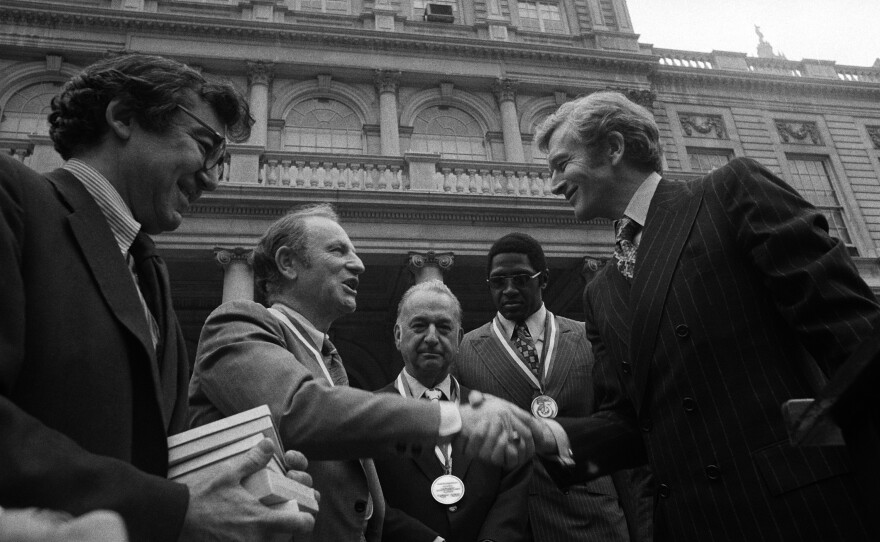 FILE - New York Mayor John Lindsay, right, congratulates Red Holzman, coach of the New York Knicks, after presenting the city's diamond jubilee medals to Holzman and other members of the Knicks team on the steps of City Hall on May 15, 1973. Shown with the mayor are Irving Felt, board chairman of Madison Square Garden, second from left, and Willis Reed, team captain, next to Lindsay.