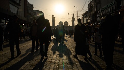 People walk toward the Kadhimiya Shrine at sunset in the Shia neighborhood in Baghdad, Tuesday.