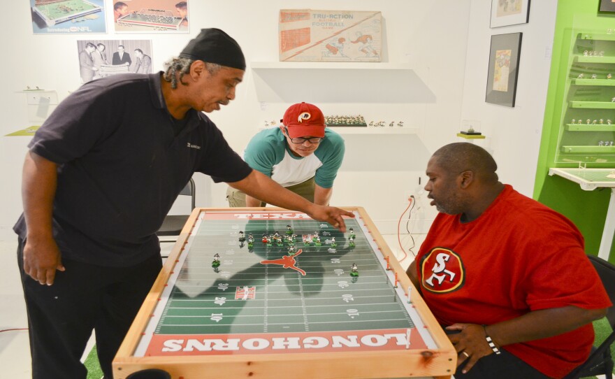 Kelvin Lomax (from left), Chris Bopst and Dru Sparks study the electric football field before a play. Their pastime of choice is on display at a museum in Richmond, Va.