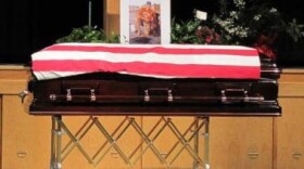 Hawkeye the dog lies by master Jon Tumilson's coffin