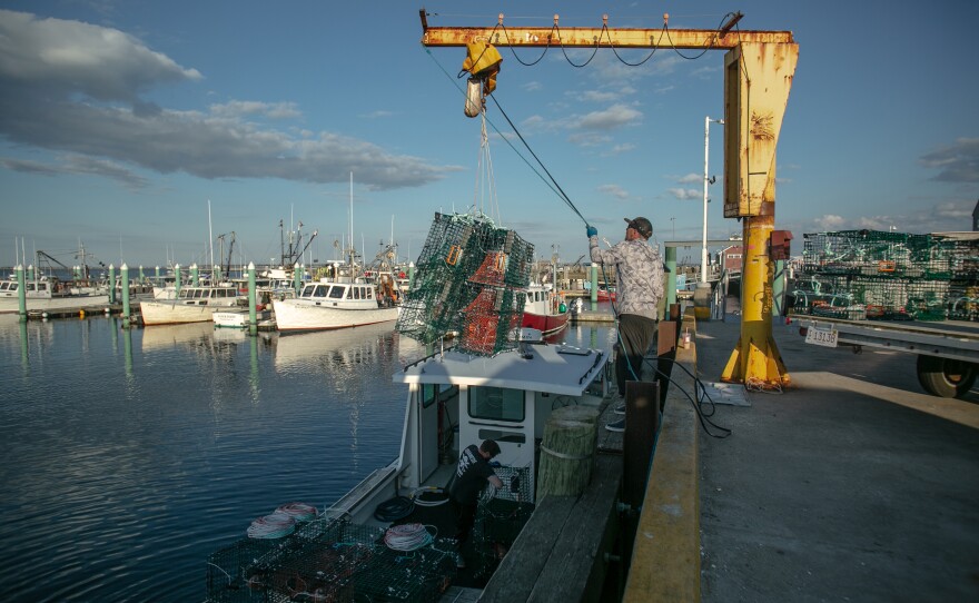 A fisherman lowers lobster traps onto a boat at MacMillian Pier in Provincetown.